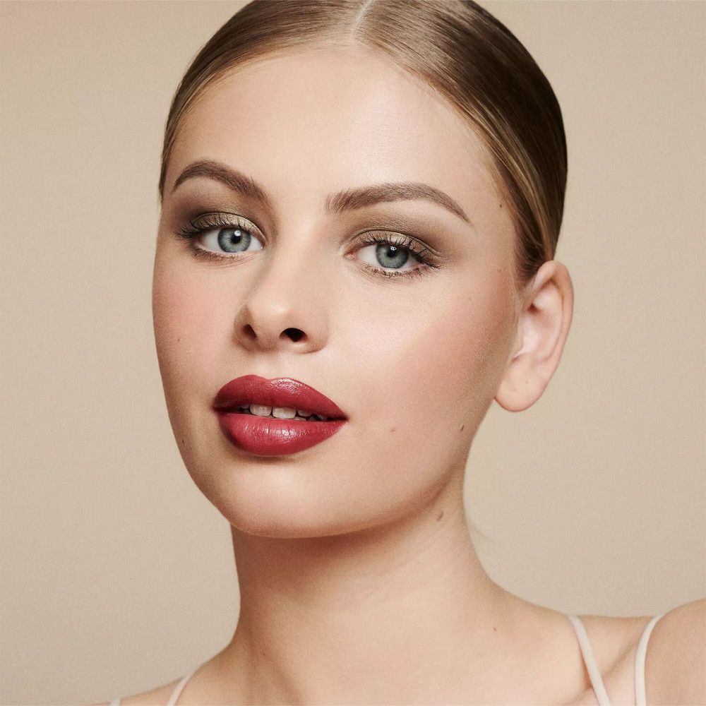 Portrait d'une femme maquillée. Fard à paupières, rouge à lèvres. Teint clair. Fond : beige.