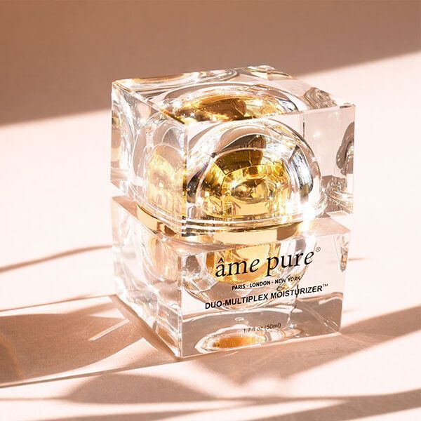 Een âme pure Duo-Multiplex Moisturizer in een transparante, vierkante verpakking met een gouden deksel. Close-up.