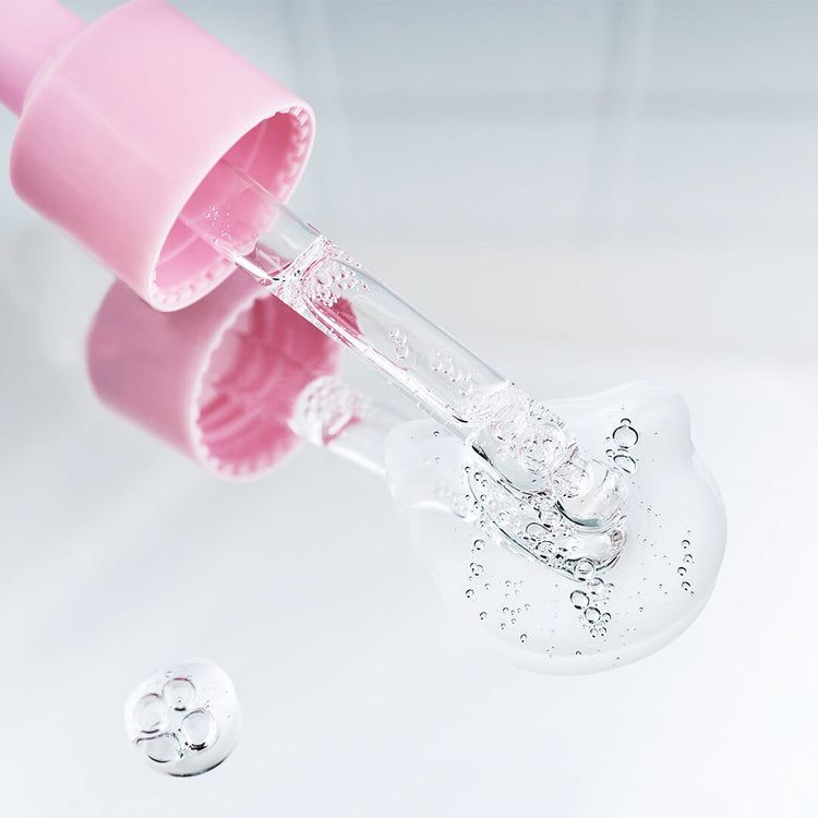 Pipette avec du sérum transparent et des bulles tombant sur une surface lisse.