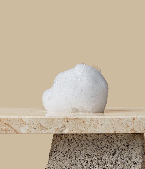 Witte schuim op een marmeren plaat. Beige achtergrond. Schuimstructuur zichtbaar.