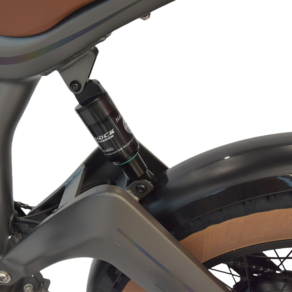 Gros plan de l'amortisseur arrière d'un dirt bike électrique gris. Détails noirs et inscription 'SHOCK'.