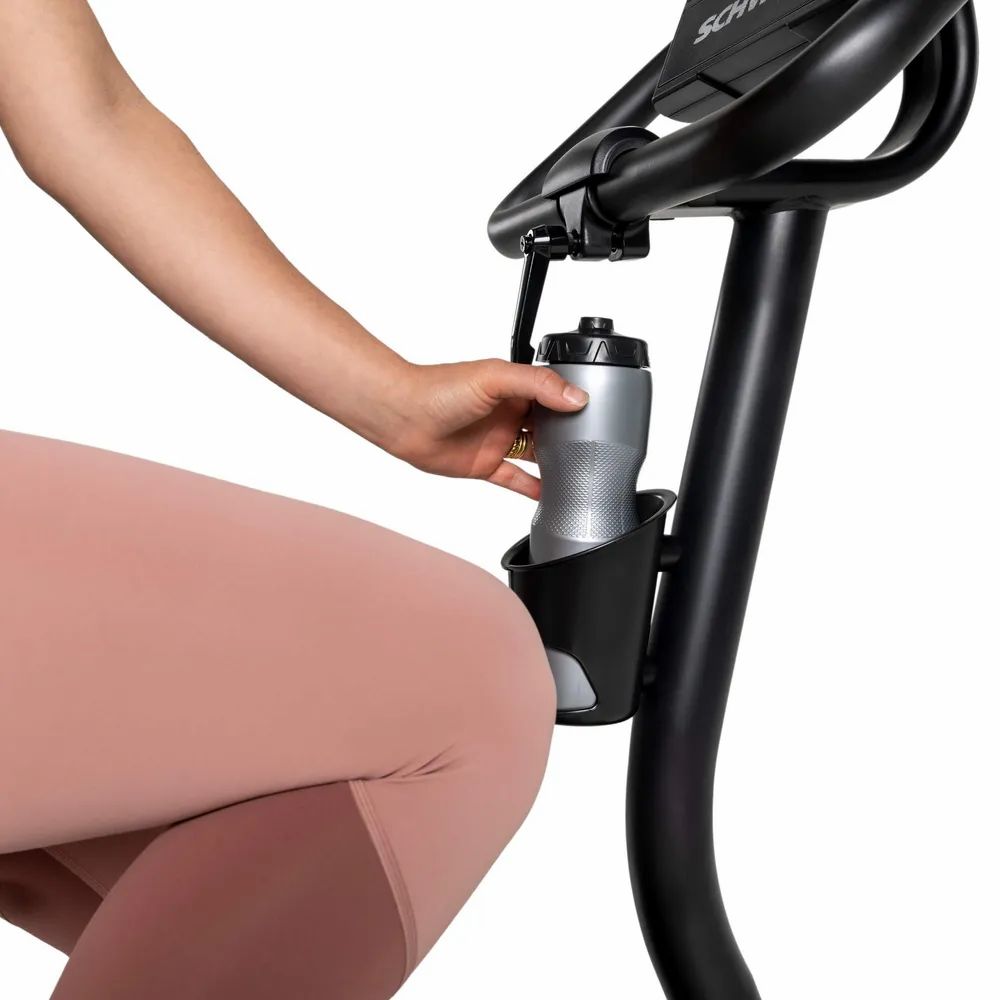 Femme prenant une bouteille d'eau sur le vélo d'appartement. Porte-bouteille noir.