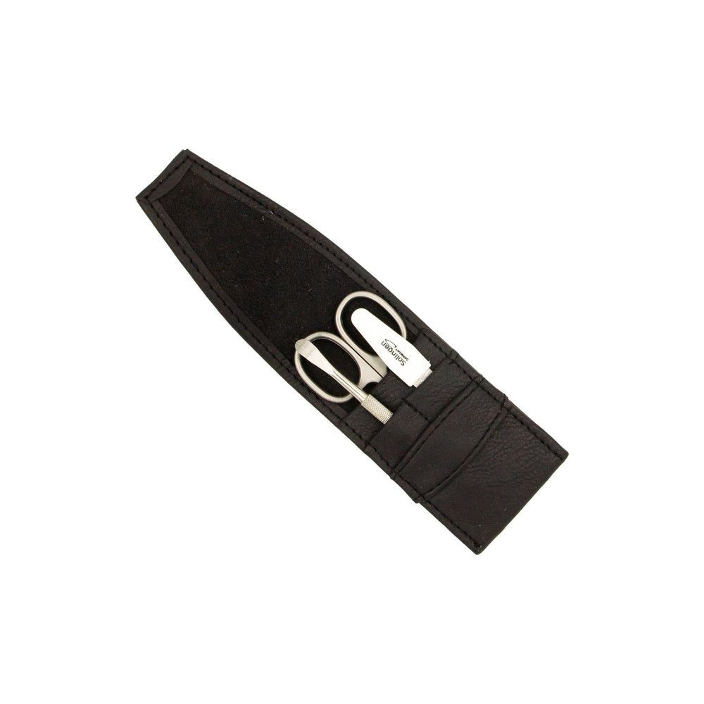 Étui noir en similicuir contenant trois instruments de manucure : ciseaux, coupe-ongles et pince à épiler.