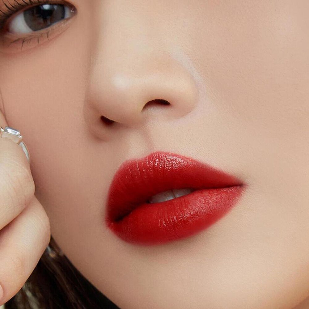 Gros plan sur des lèvres maquillées avec un gloss rouge. Les lèvres sont pleines et brillantes.