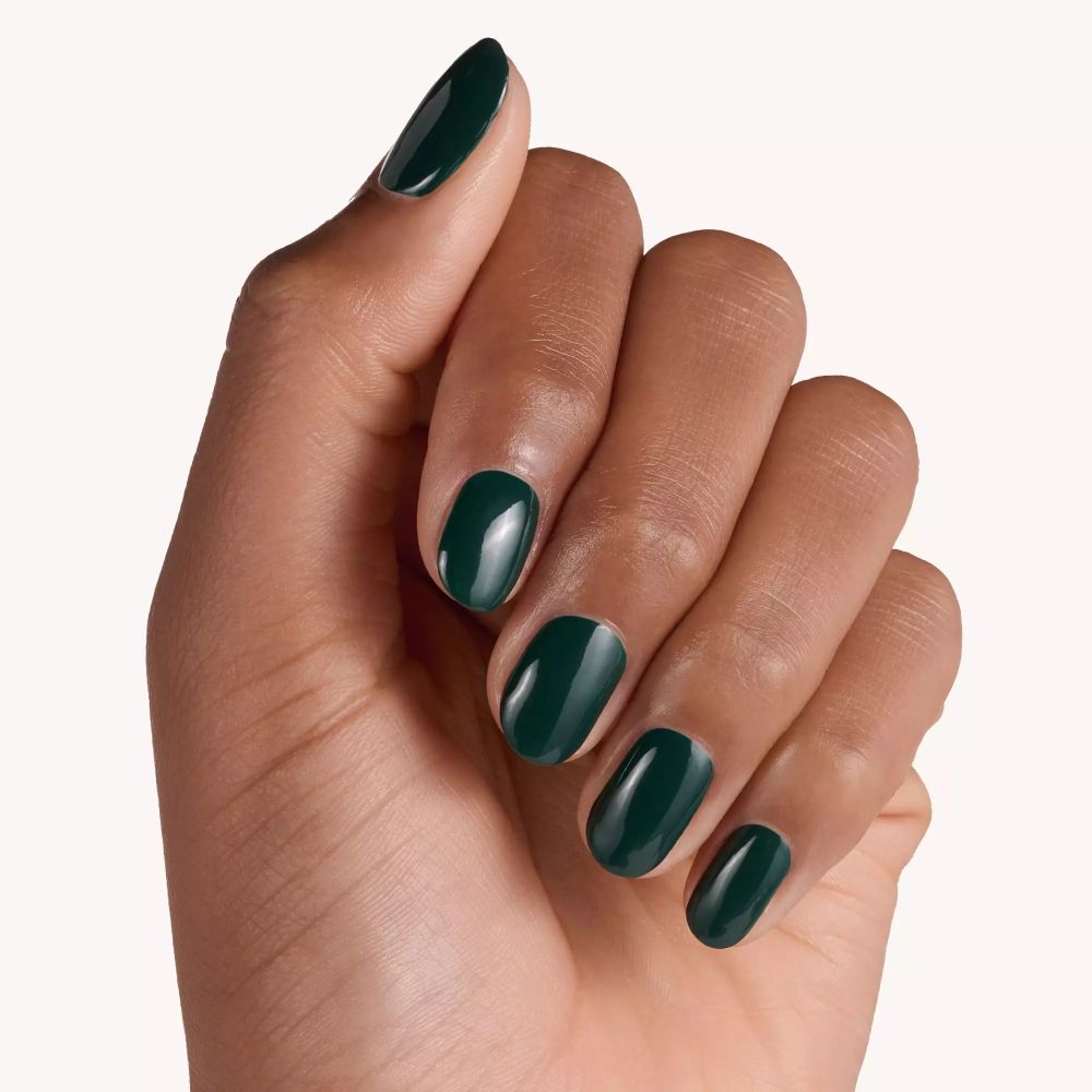 Main avec ongles vernis en vert. Tous les ongles sont recouverts de vernis à ongles vert.