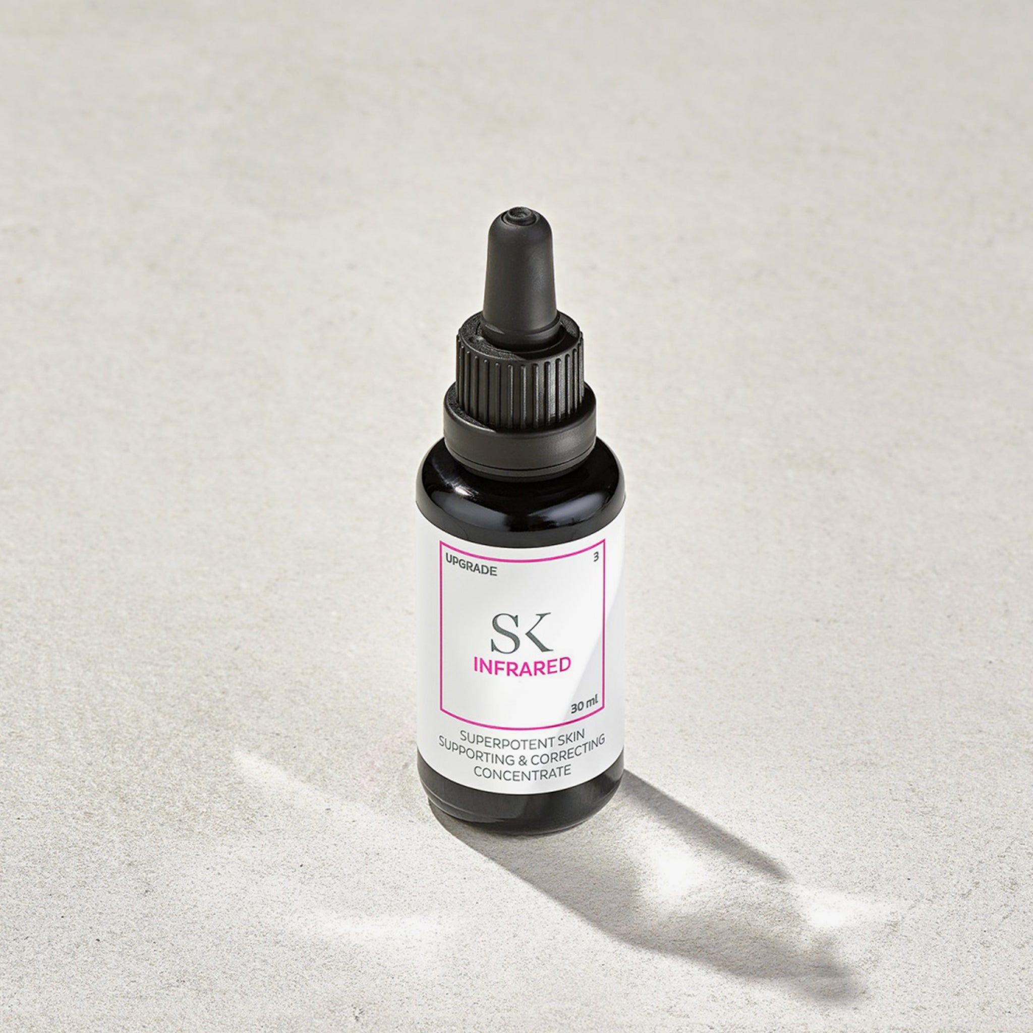 Flacon en verre noir avec bouchon et pipette noirs. Étiquette avec "SK INFRARED" et texte. 30 ml.