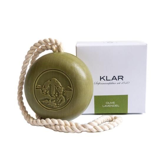 Ronde groene zeep met koord, naast een witte verpakking met Klar-logo en label Olijf/Lavendel.