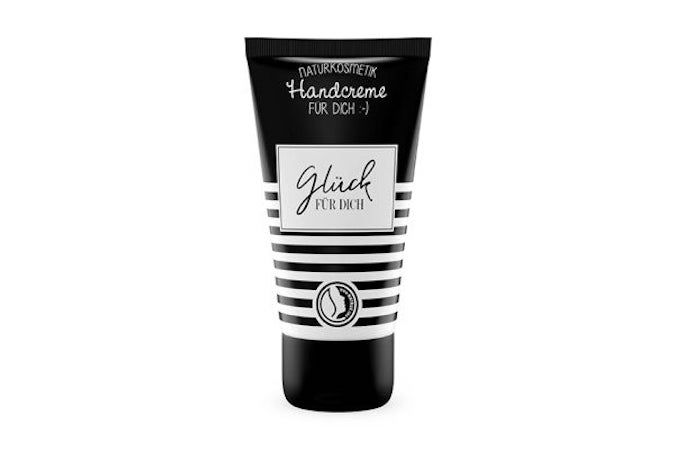 Zwarte handcrèmetube met witte tekst. Opschrift: Naturkosmetik, Handcreme, Glück für Dich. Strepenpatroon en logo.