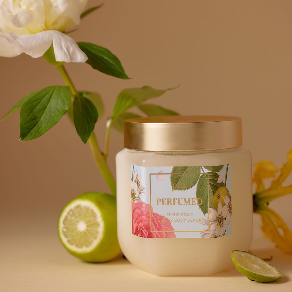 Pot en verre avec couvercle doré, à côté d'un citron vert et d'une fleur. Étiquette avec motif floral et texte.