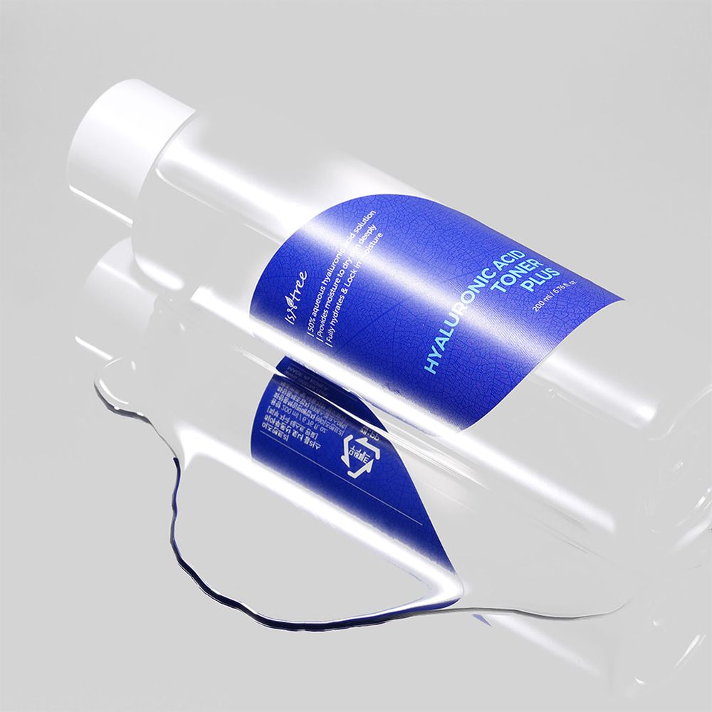 Flacon transparent avec étiquette bleue. Inscription: Hyaluronic Acid Toner Plus. Liquide sur surface lisse.