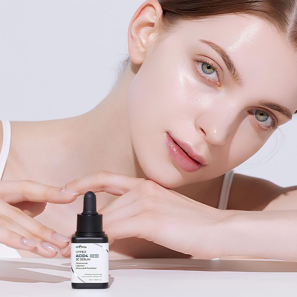 Femme avec flacon de sérum. Image du produit : ISNTREE Hyper Acid4 30 Serum. La femme se touche le visage.