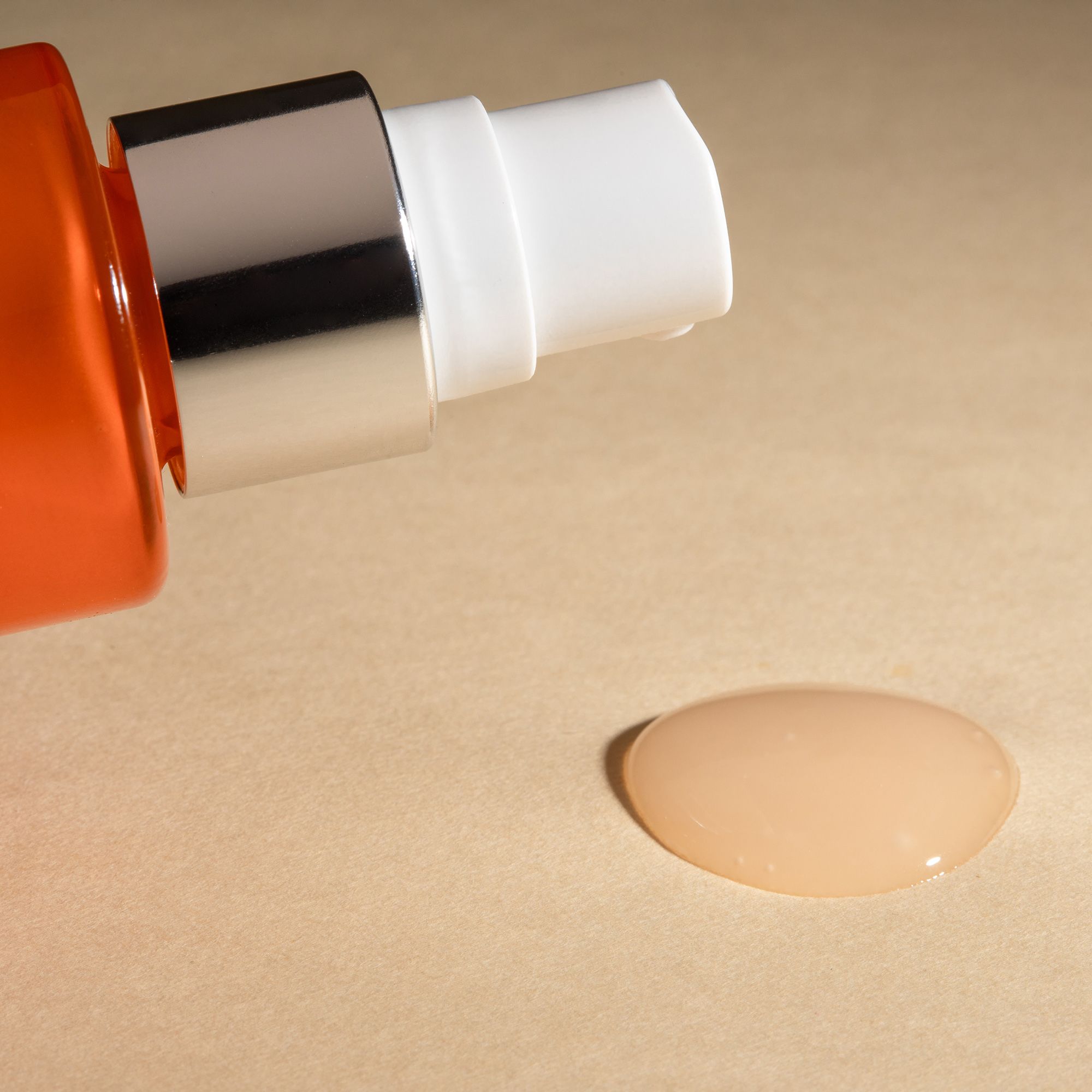 Serumdruppel. Druppel serum op beige achtergrond. Fles met verstuiver op de achtergrond.