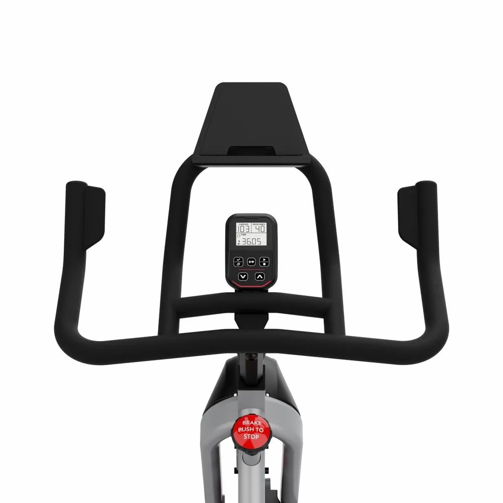 Vélo d'intérieur gris de face, focus sur le guidon, l'écran et la roue d'inertie.
