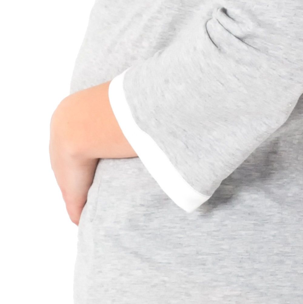 Gros plan sur la chemise de grossesse grise chinée à manches longues. Ourlet blanc sur la manche.