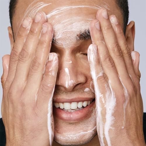 Homme se lavant le visage avec de la mousse. Yeux fermés, mains couvertes de mousse.