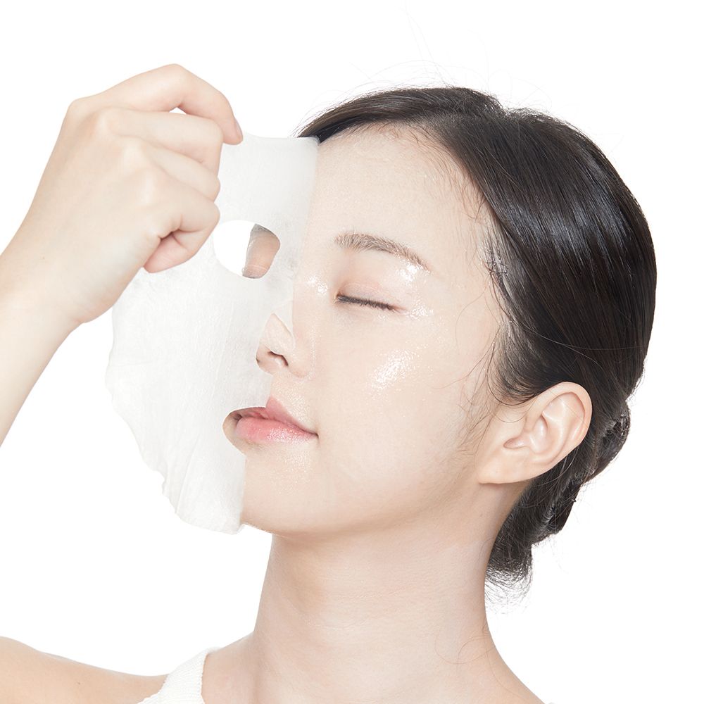 Gezichtsmasker wordt op het gezicht van een vrouw aangebracht. Het masker bedekt de helft van het gezicht. Ogen gesloten.
