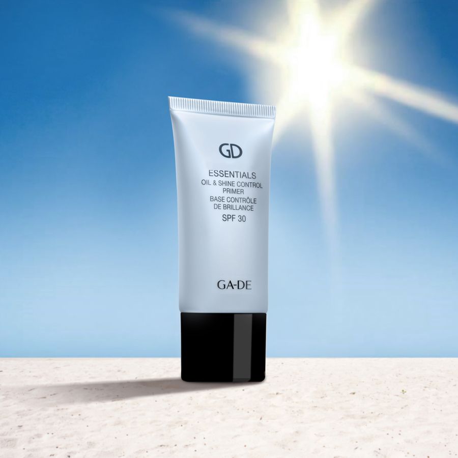 Tube de primer devant un soleil. Inscription: GD Essentials Oil & Shine Control Primer SPF 30. Bouchon noir.