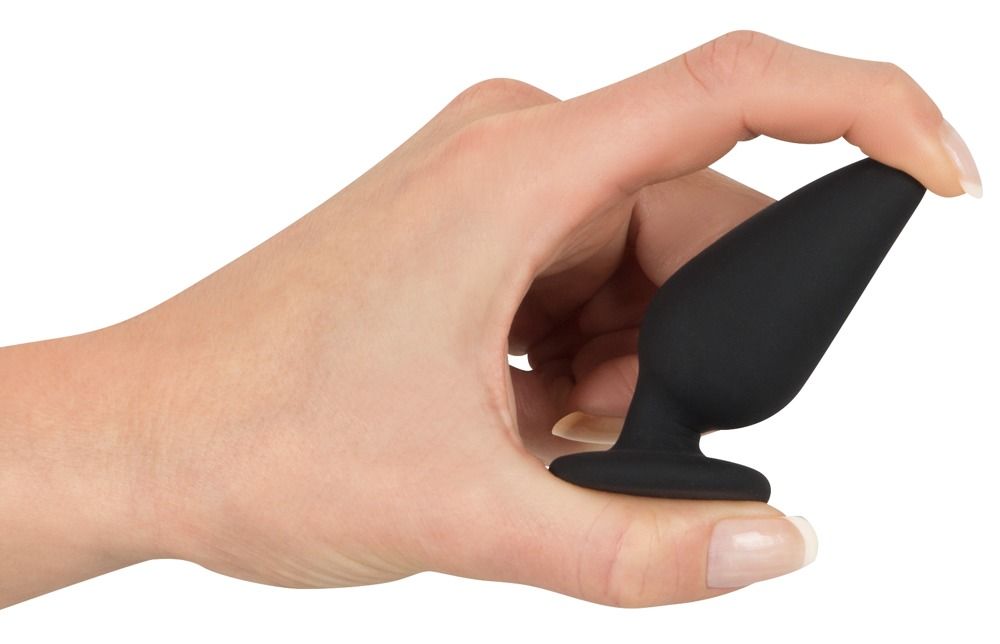 Hand die een zwarte anale plug vasthoudt, gemakkelijk vast te pakken.