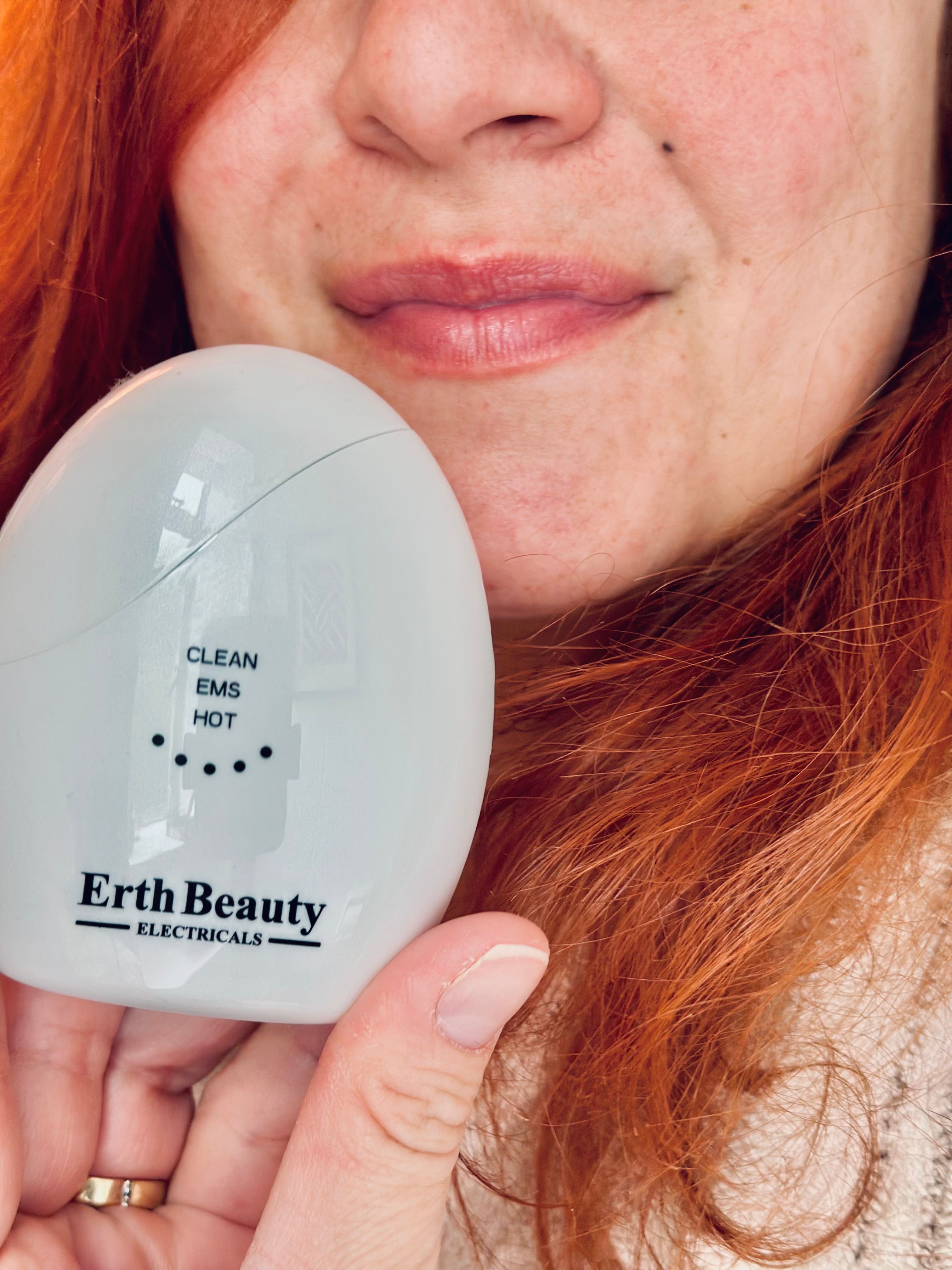 Appareil blanc ovale avec inscription : CLEAN, EMS, HOT. Marque : Erth Beauty Electricals. Appareil tenu.