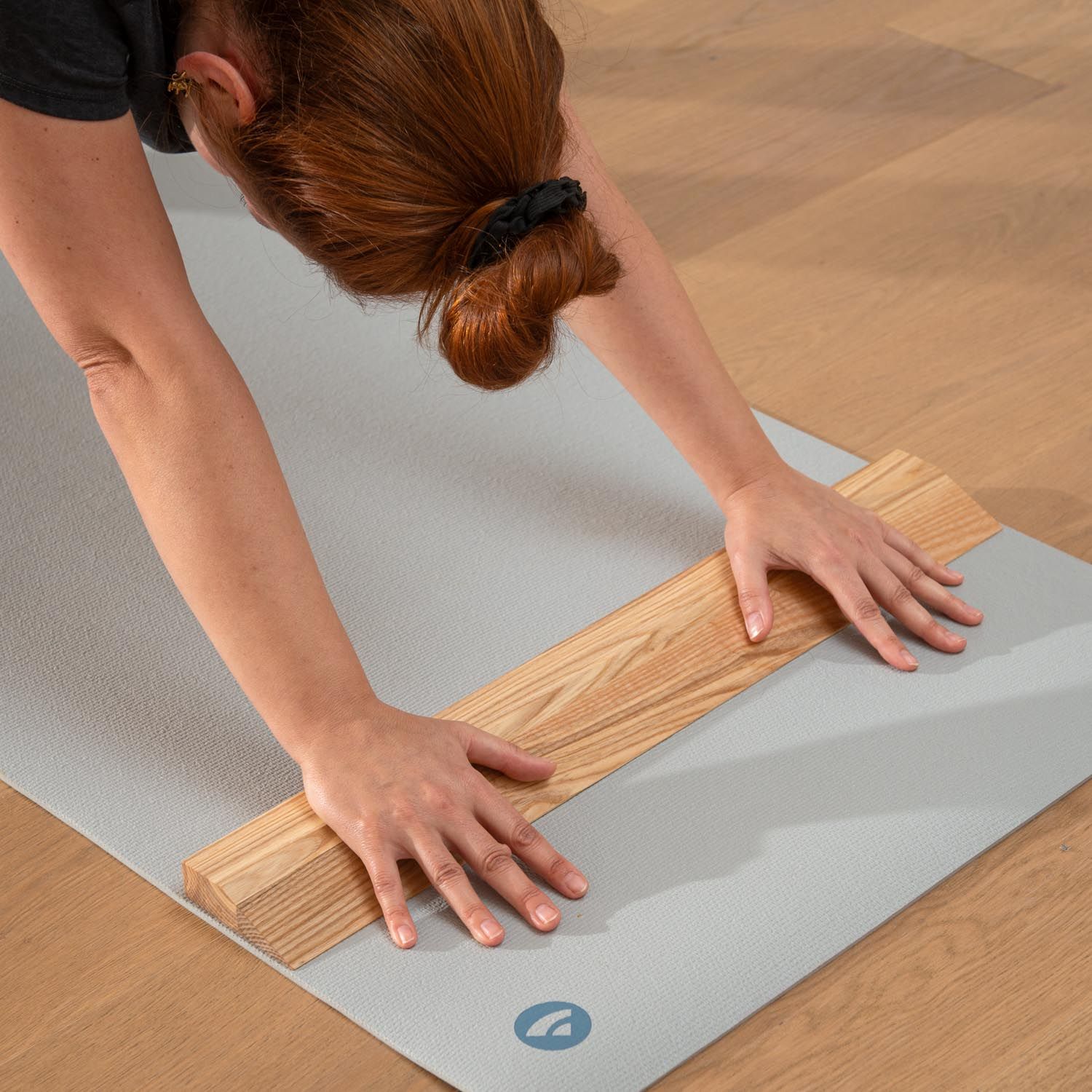 Persoon met handstandplank op yogamat. Lichtbruin hout. Grijze mat. Persoon in yoga-positie.