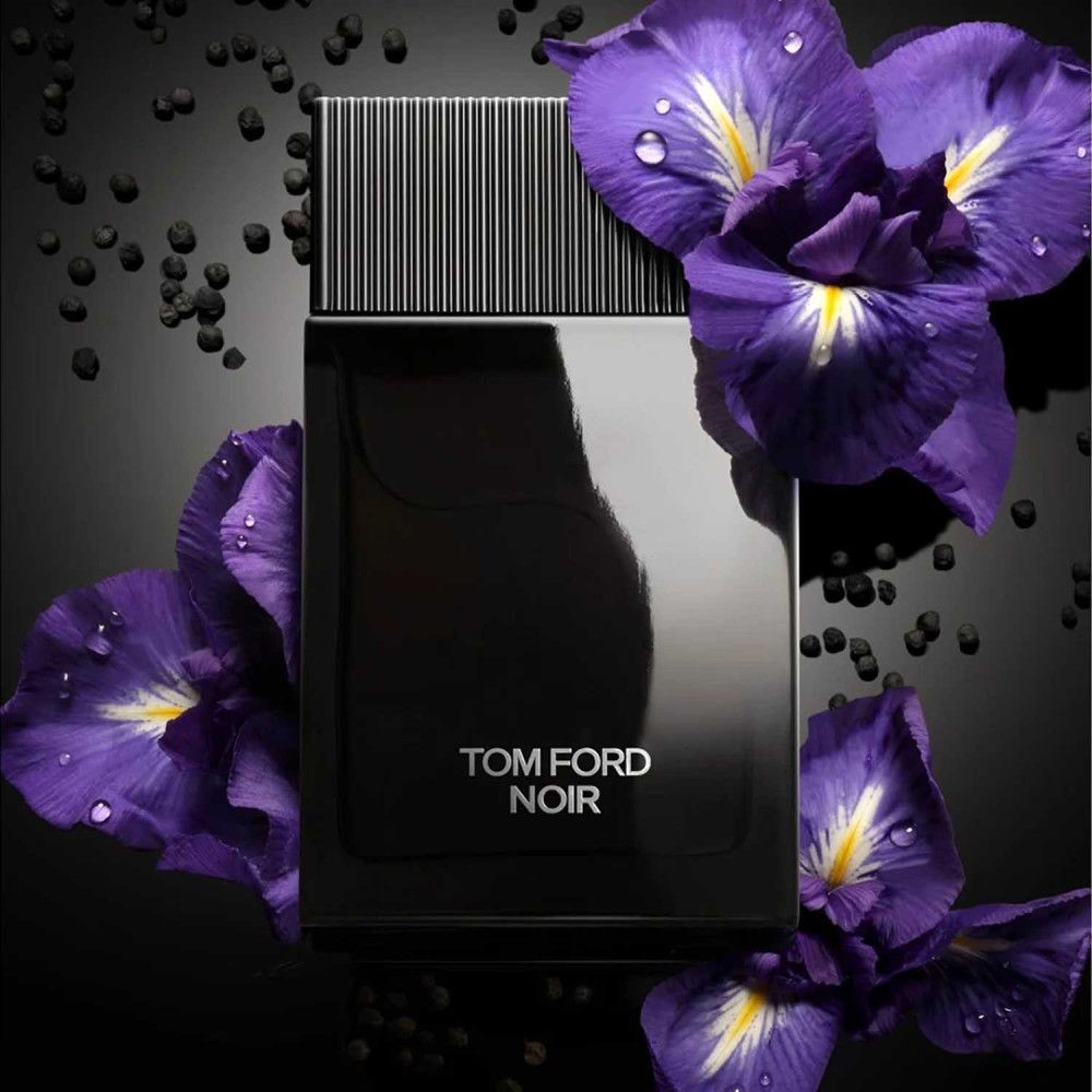 Flacon noir avec bouchon noir. Inscription TOM FORD NOIR en blanc. Entouré de fleurs violettes.