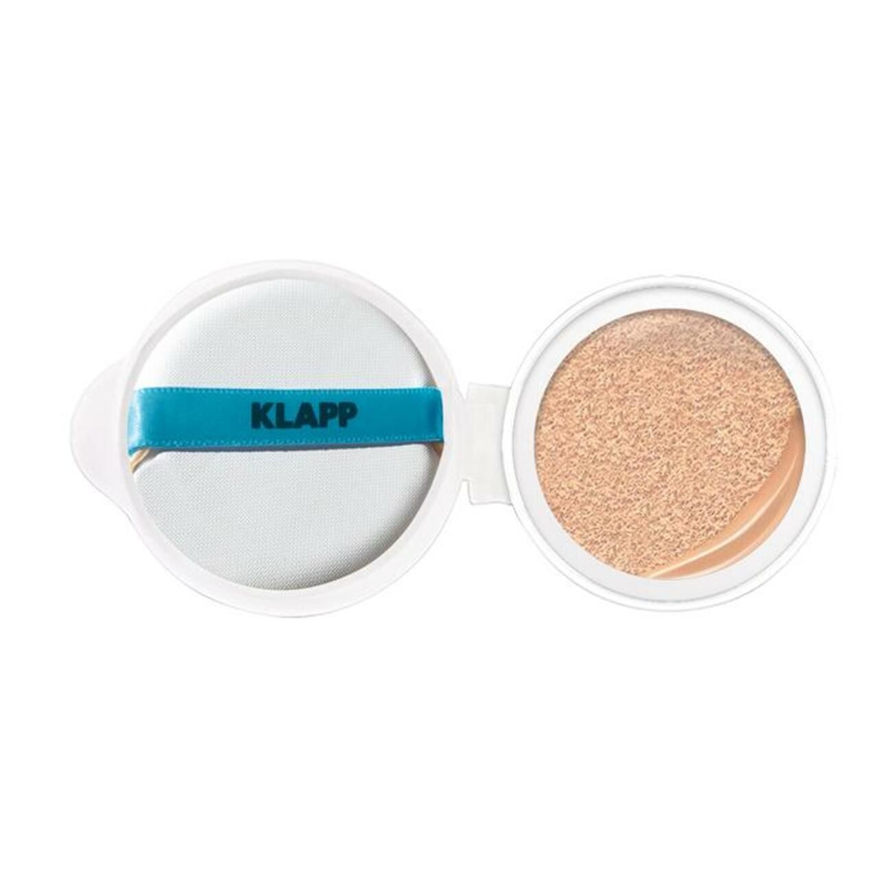Open witte cosmeticaverpakking met spons en getint product. De spons heeft een blauwe band met de tekst KLAPP.