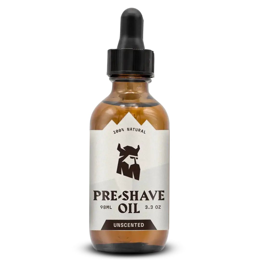 Bruine glazen fles met zwarte druppelaar. Etiket met logo en tekst: PRE-SHAVE OIL, UNSCENTED. 100% Natural.