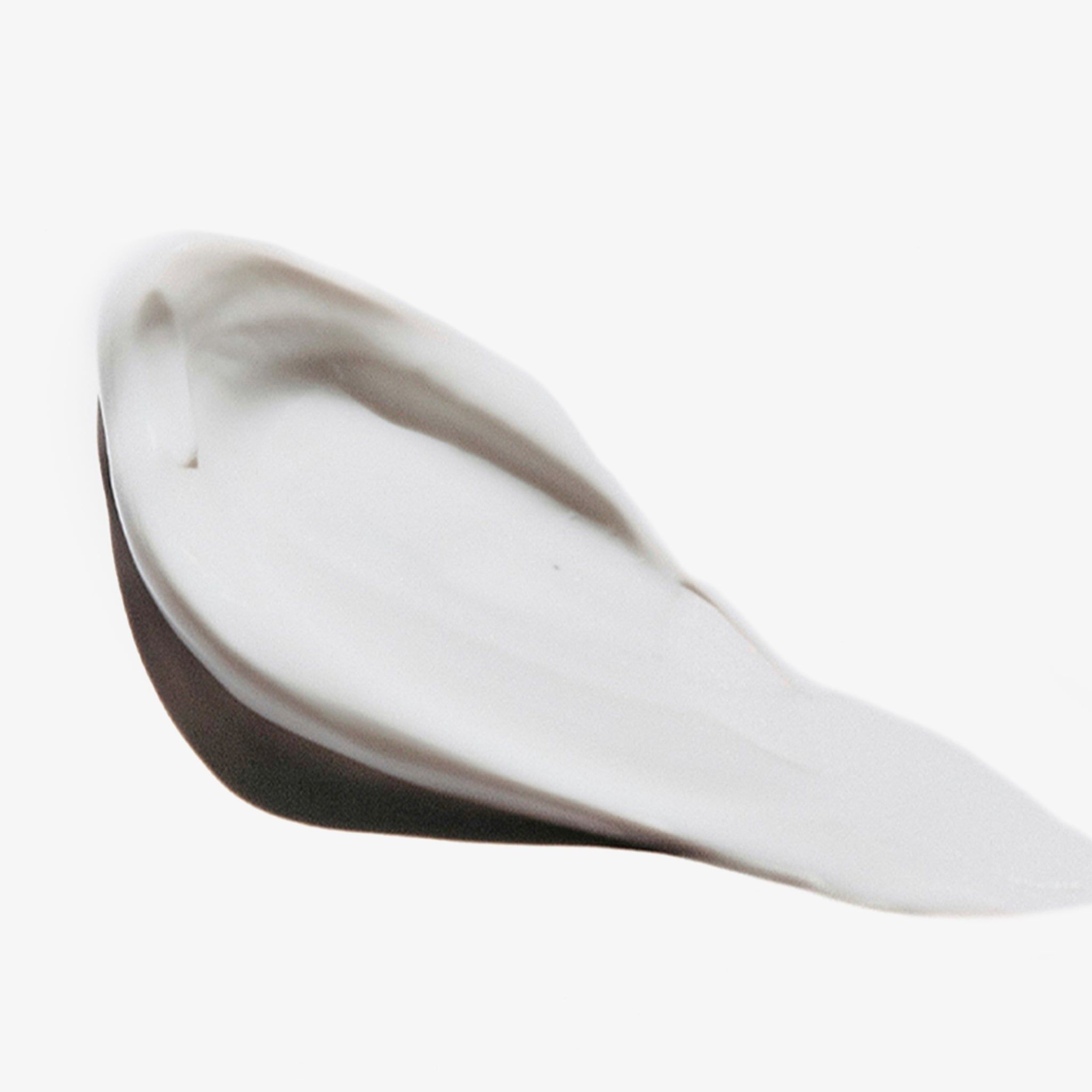 Éclaboussure de revitalisant blanc sur fond blanc. Texture lisse, légèrement brillante.
