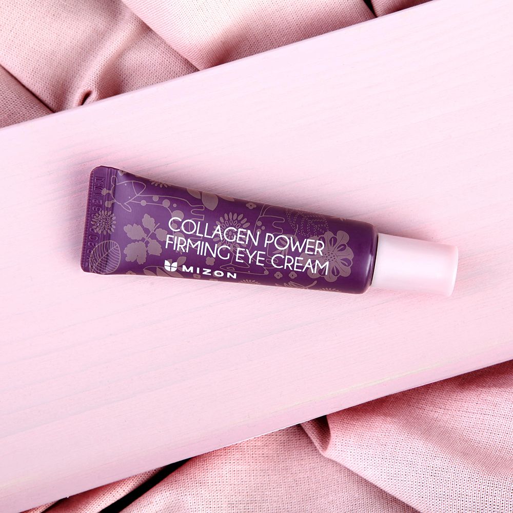 Paarse tube met bloemmotief. Gedrukt: Collagen Power Firming Eye Cream. Merk MIZON. Op roze achtergrond.