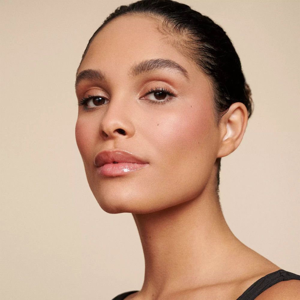 Portrait d'une femme à la peau bronzée. Maquillage naturel, joues roses, lèvres brillantes.