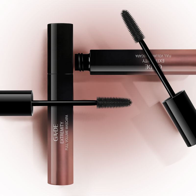 Trois tubes de mascara. Deux avec brosses sorties. Inscription: GA-DE Extremity Full Volume Mascara. Fond rose.