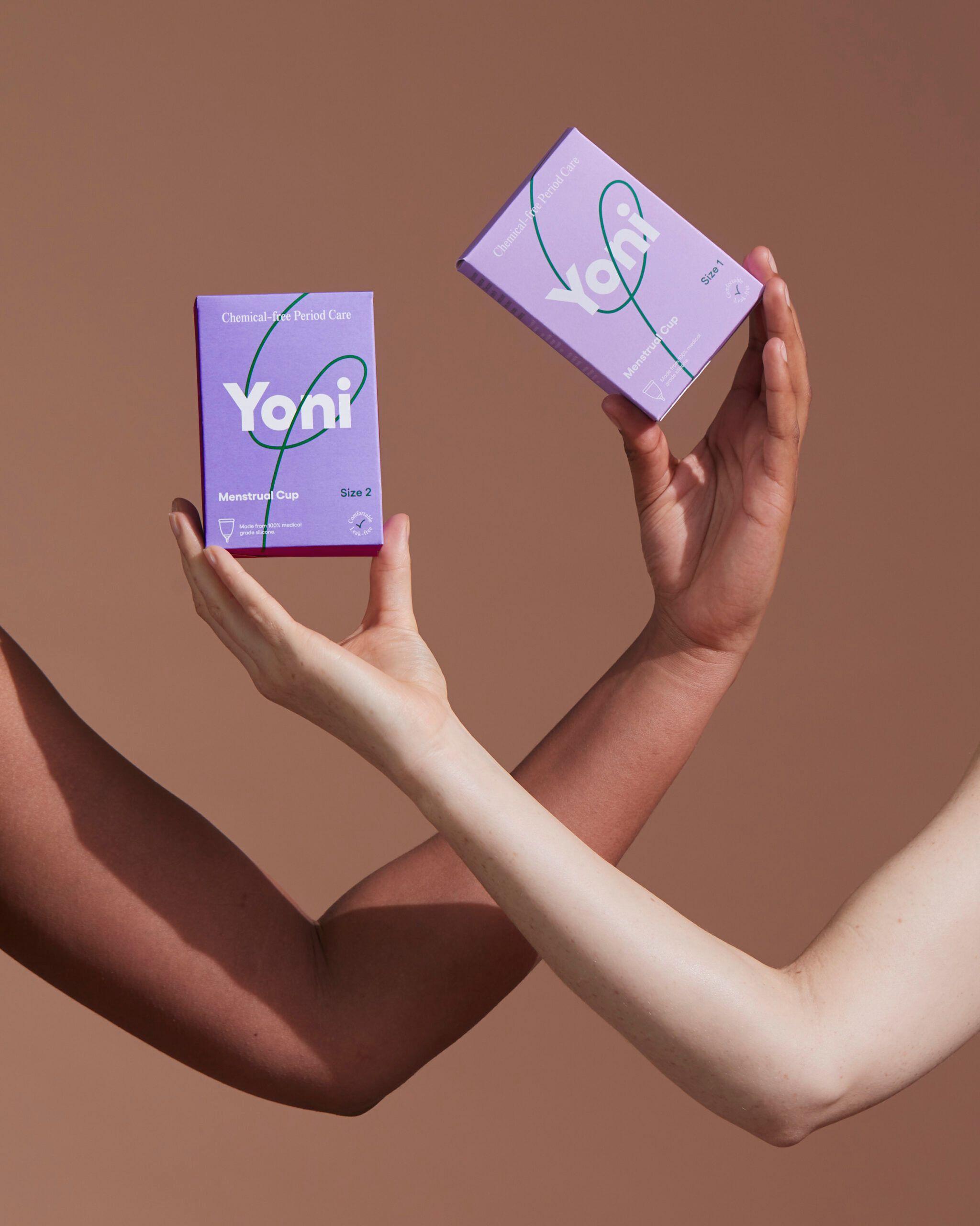 Deux mains tenant des boîtes Yoni violettes. Inscription : coupe menstruelle, taille 2.