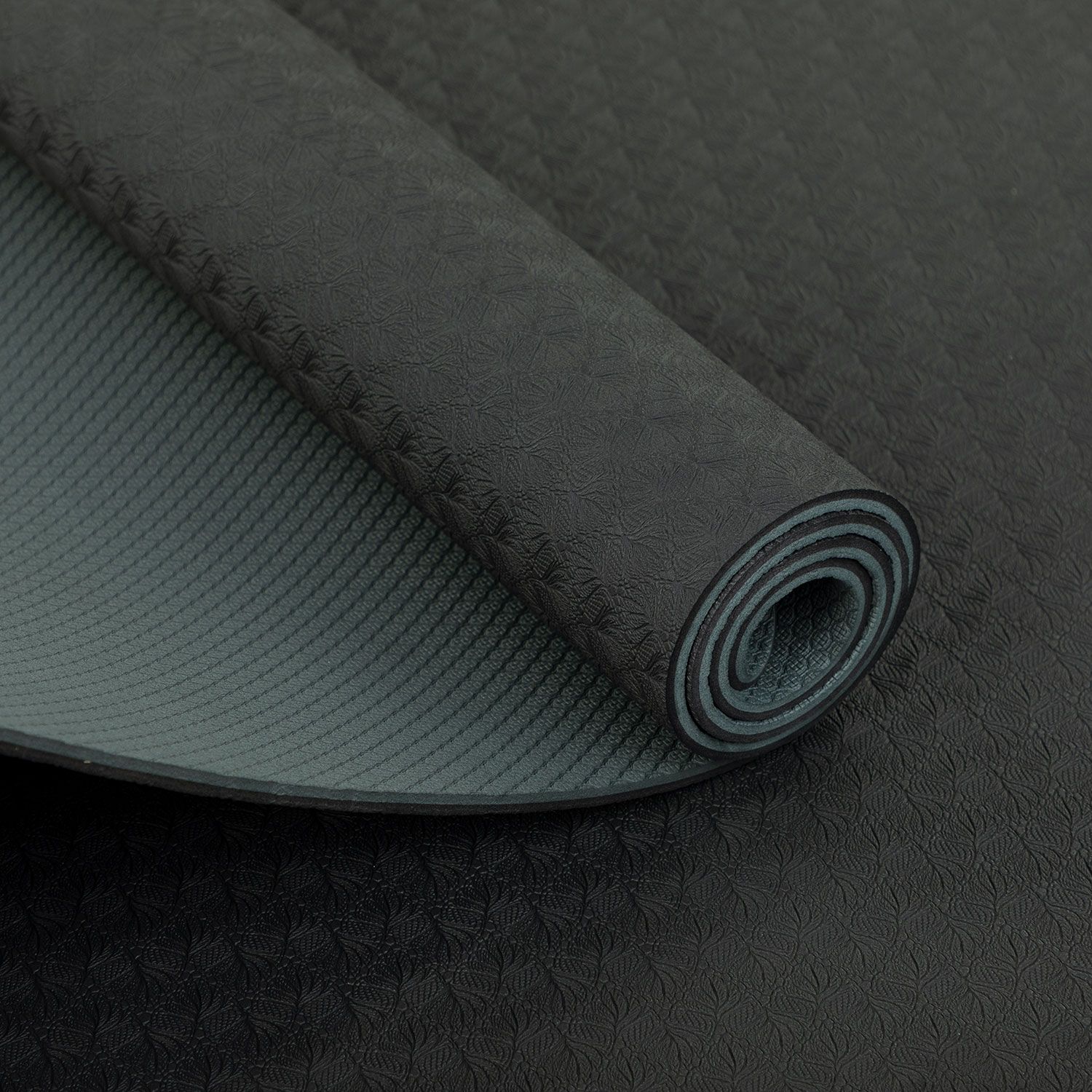 Yogamat, opgerold. Antracietkleurige bovenkant met patroon, grijze onderkant. Detailweergave.