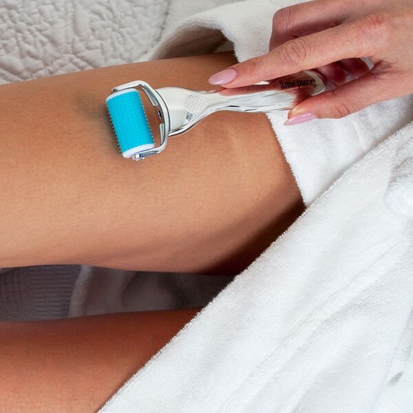 Hand houdt een CIT roller met zilverkleurig handvat en blauwe rolkop op de huid.