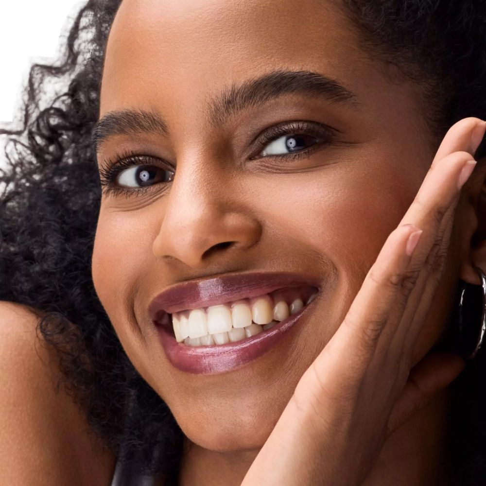 Vrouw met donkere huid en lipstick. Lippen in donkerrood. Product zichtbaar.