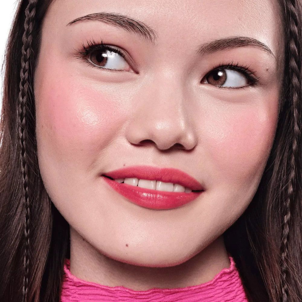 Portrait d'une femme avec lèvres et joues roses. Elle porte un haut rose. Ses yeux sont légèrement de côté.