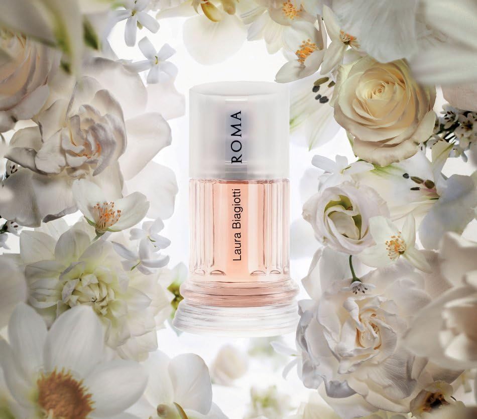 Parfumflesje omringd door witte bloemen. Roze vloeistof, cilindrische vorm, doorzichtige dop, opschrift ROMA.