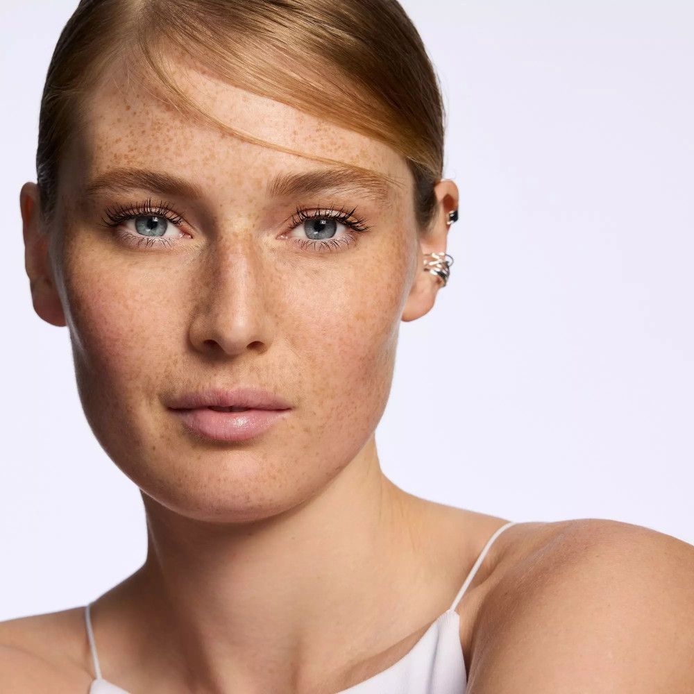 Portrait d'une femme aux cheveux blonds et taches de rousseur. Elle regarde la caméra.