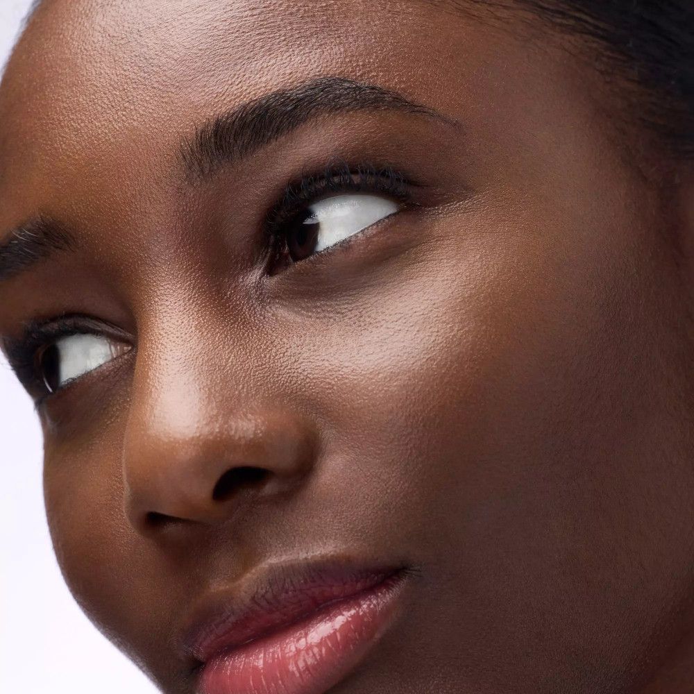 Gros plan d'un visage. Peau foncée, regard de côté. Sourcils, lèvres.