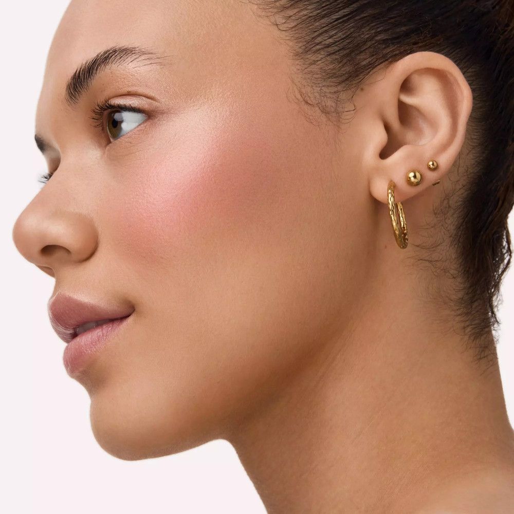 Portret van een vrouw met blush op de wangen. Gouden oorbellen. Zijaanzicht.