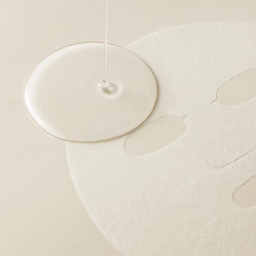 Une goutte de liquide tombe sur un masque facial. Le masque a des ouvertures pour les yeux, le nez et la bouche.