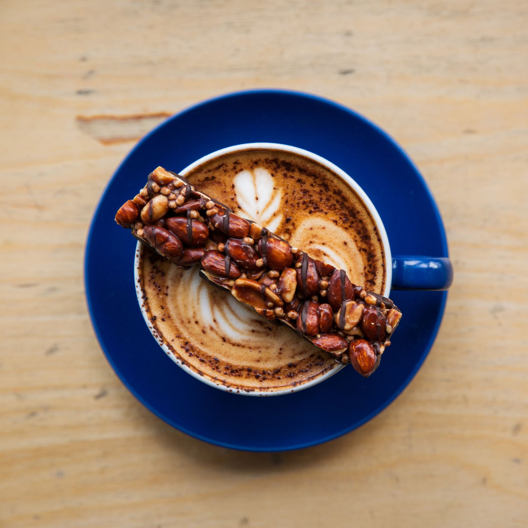 Reep op een kopje koffie met melkschuim. Reep met noten en chocolade.