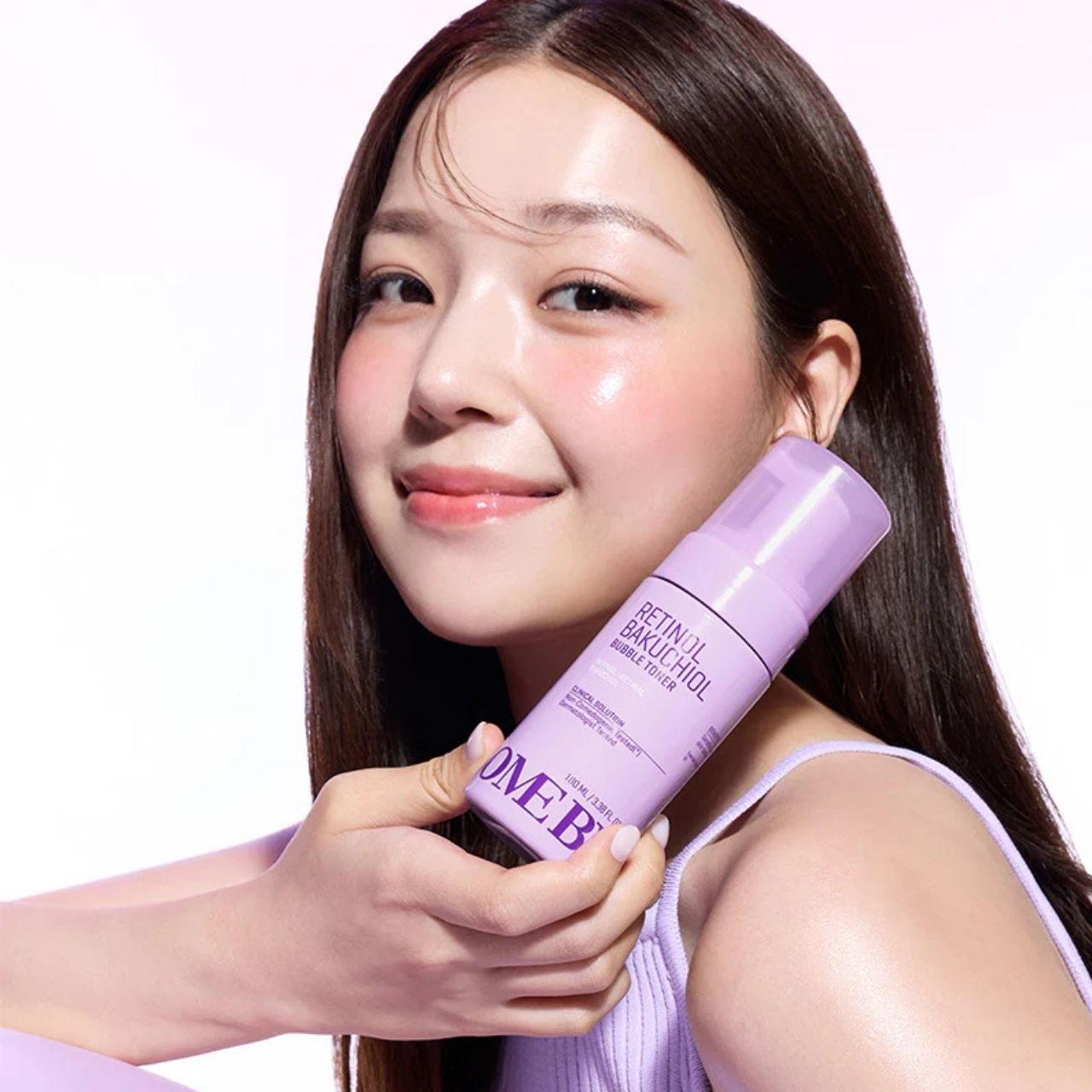 Une femme tient un flacon du toner moussant Retinol Bakuchiol de SOME BY MI.