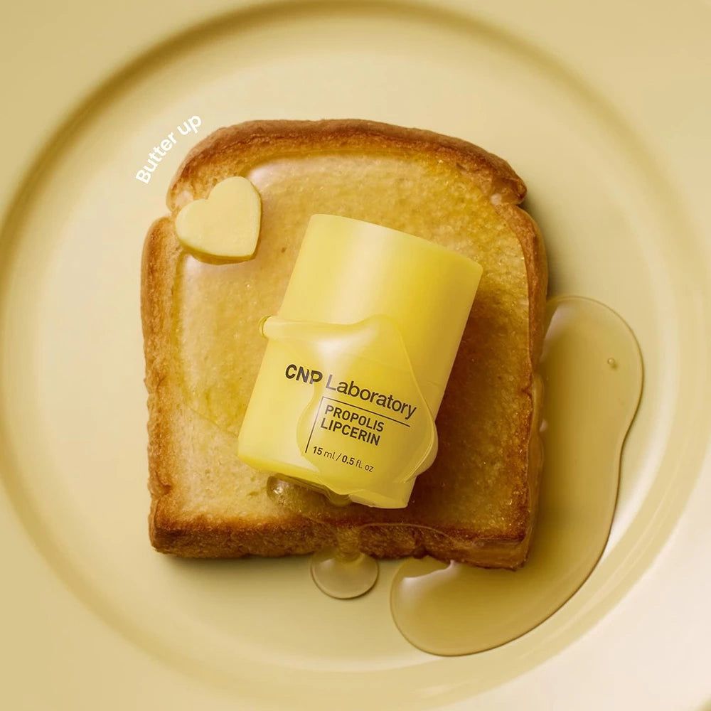 Baume à lèvres jaune sur toast beurré. Texte: CNP Laboratory PROPOLIS LIPCERIN 15 ml.