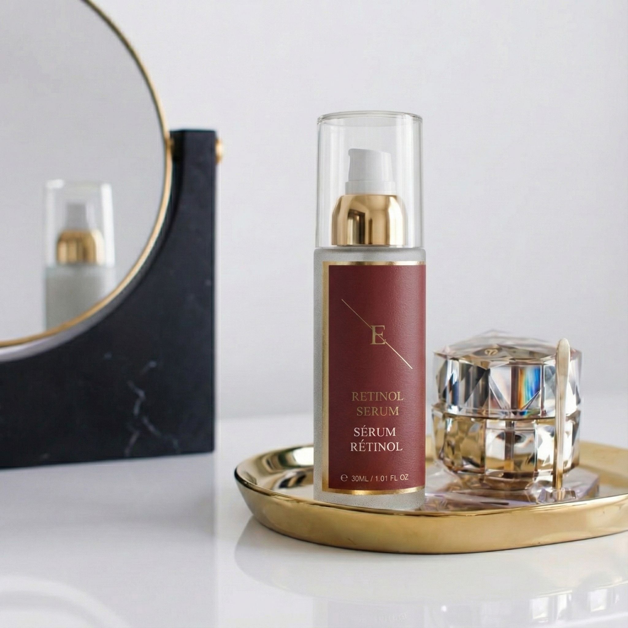 Serumfles op gouden schaal, naast sieradendoos en spiegel. Rood etiket met tekst: Retinol Serum, Sérum Rétinol.