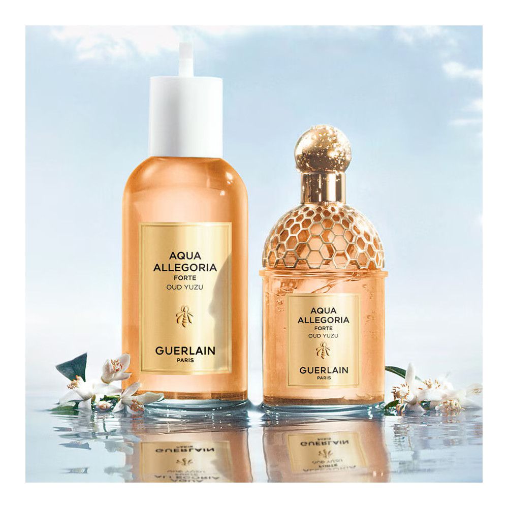 Twee flacons. Rechts: Gouden honingraatpatroon. Links: Witte sluiting. Gouden etiketten. Tekst: AQUA ALLEGORIA FORTE OUD YUZU, Guerlain.