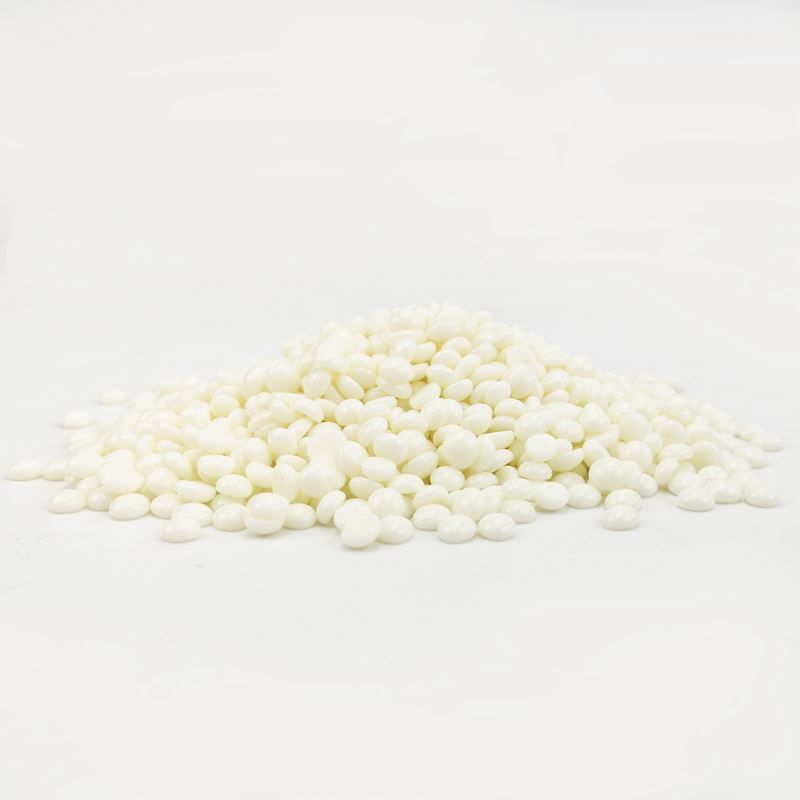 Une pile de pastilles de cire blanche sur fond blanc.