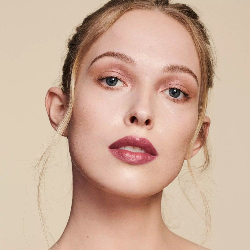 Close-up van een vrouw met een lichte huid. Ze draagt lippenstift. Haar haar is vastgebonden.