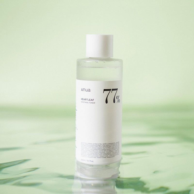 Witte fles met heldere vloeistof, witte dop. Opschrift: anua, 77%, Heartleaf Soothing Toner. Groene achtergrond.