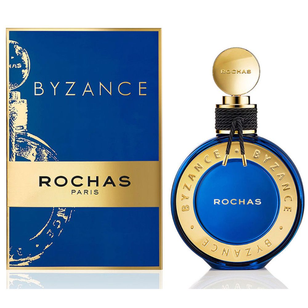 Blauw-gouden parfumfles en verpakking. Opschrift: BYZANCE, ROCHAS PARIS. Ronde fles met gouden dop en zwart lint.